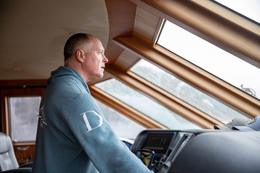 Alaska charter captain guiding vessel through Southeast Alaska waters from the wheelhouse
