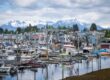 Fishing boats fill the harbor in Petersburg, Alaska, with the town and snow-covered mountains behind.